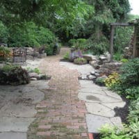 Narrow Yard Features Brick Walkway and Stone Relic Wall